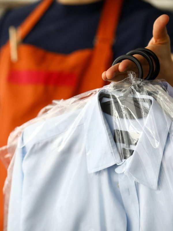 Clothes dry cleaning service worker returning shirts to customer close-up